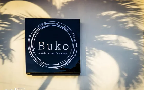 Signage of Buko Seaside with a coconut tree's shadow in the background