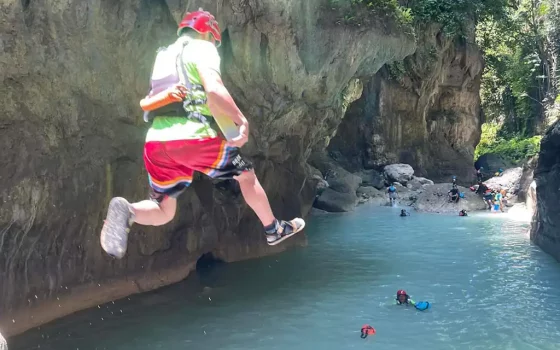 A tour guide dives into the turquoise waters of Kawasan Falls