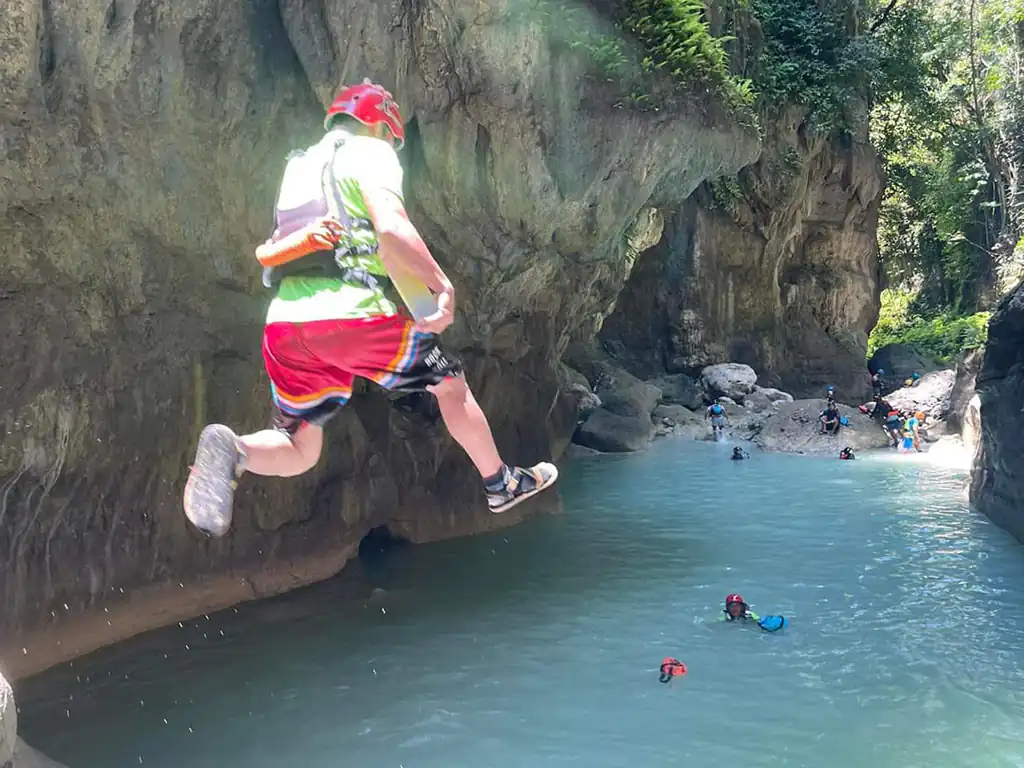 A tour guide dives into the turquoise waters of Kawasan Falls
